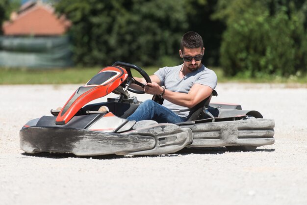 Молодой человек за рулем автомобиля GoKart со скоростью на игровой площадке Гоночный трек Go Kart - популярный вид автоспорта