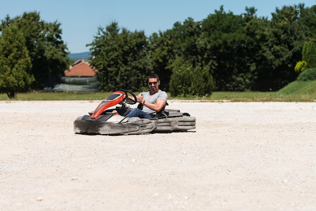 젊은 남자가 운동장 경주 트랙에서 속도로 GoKart 자동차를 운전하고 있습니다. Go Kart는 인기 있는 레저 모터 스포츠입니다.