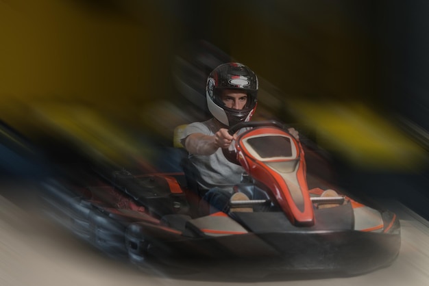 Молодой человек за рулем автомобиля GoKart со скоростью на игровой площадке Гоночный трек Go Kart - популярный вид автоспорта