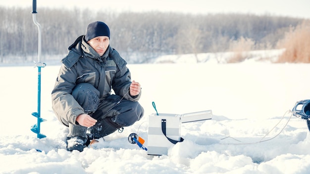 A young man is fishing from a hole on ice Winter fishing