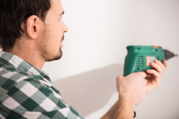 Young man is holding electric drill.