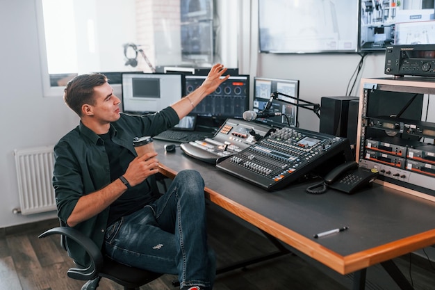 写真 若い男はラジオスタジオの屋内にいて放送で忙しい