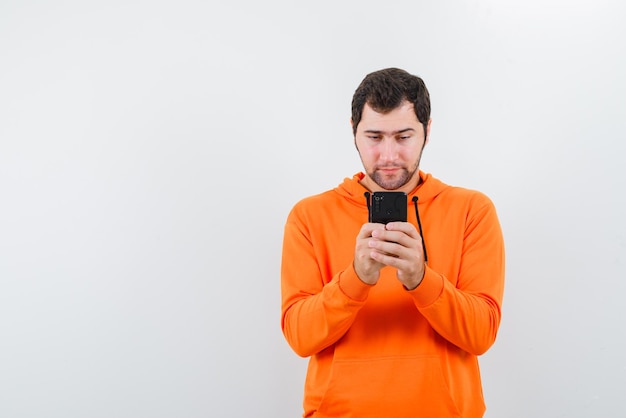 The young man is looking at mobile phone on white background