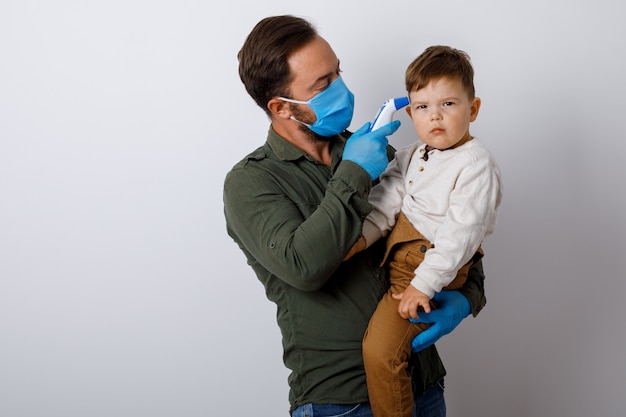 Young man is measuring body temperature of a toddler boy