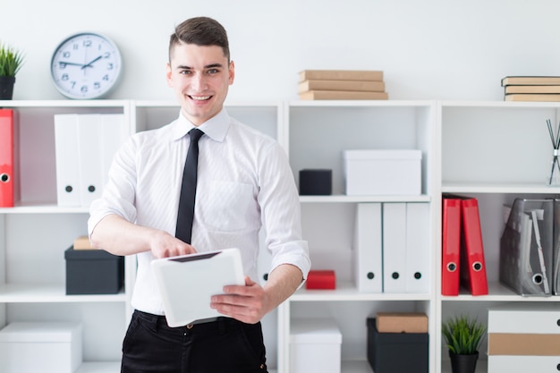 The young man is in the office and holding a tablet.