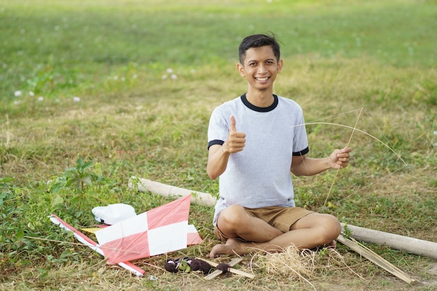 A young man is preparing a bamboo stick for a kite