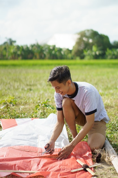 A young man is preparing a bamboo stick for a kite