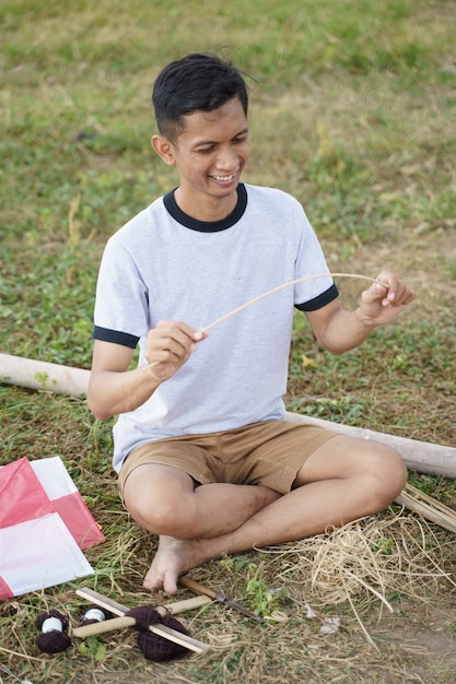 A young man is preparing a bamboo stick for a kite