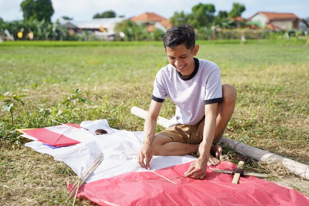 A young man is preparing a bamboo stick for a kite