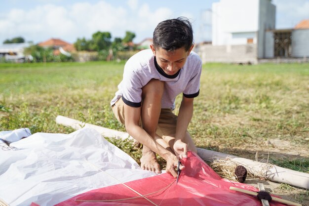 A young man is preparing a bamboo stick for a kite