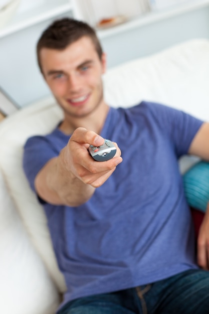 Young man is relaxing in the livingroom with remote