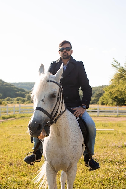 若い男は農場で馬に乗っています