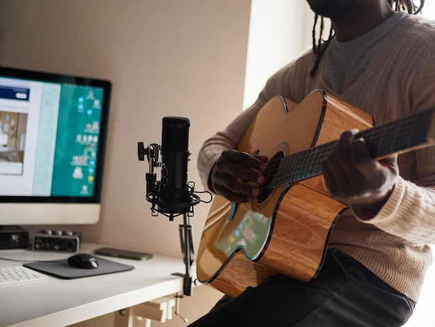 Young man is singing and playing guitar while making an audio recording at home