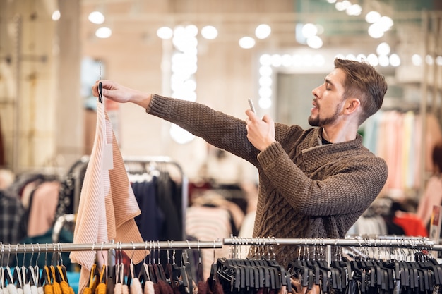 A young man is taking a picture of an item at a clothing store