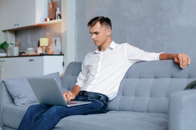 Il giovane sta lavorando su un laptop nel suo appartamento. vita domestica.