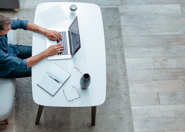 Il giovane sta lavorando su un laptop nel suo appartamento persone e tecnologia