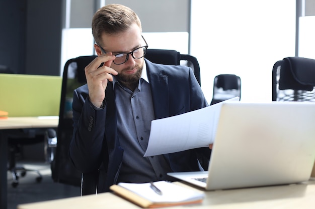 Young man is working with papers while sitting in the office.