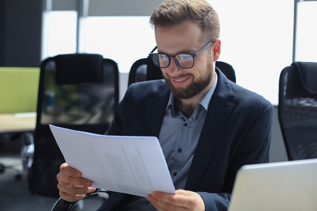 Young man is working with papers while sitting in the office.