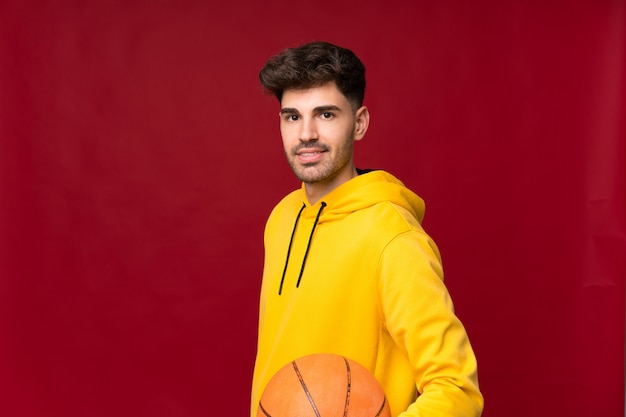 Young man over isolated background with ball of basketball