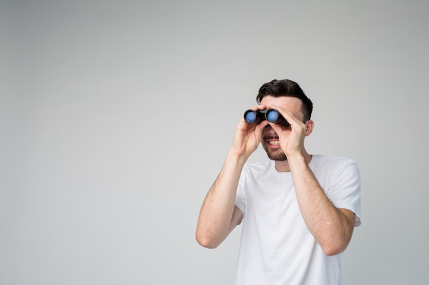 Foto giovane uomo isolato su sfondo con il binocolo