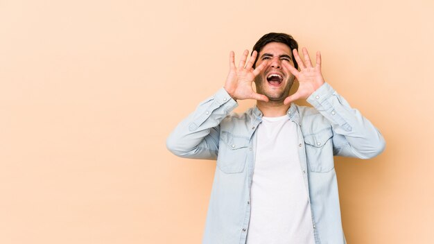 Young man isolated on beige shouting excited to front.