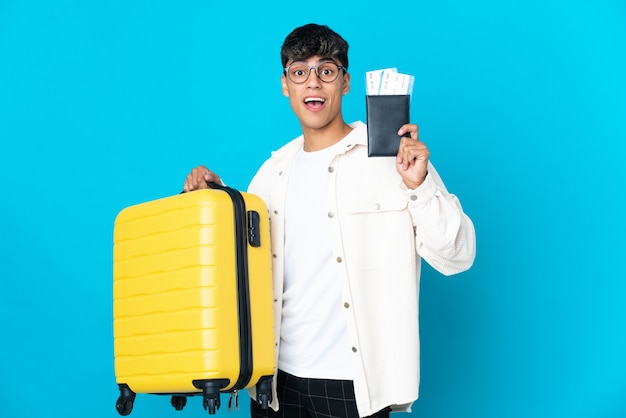 가방 및 여권 휴가에 고립 된 파란색 배경 위에 젊은 남자