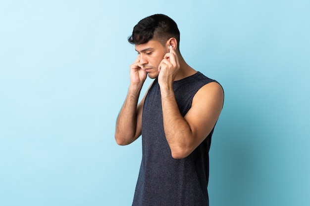 Young man isolated on blue listening music