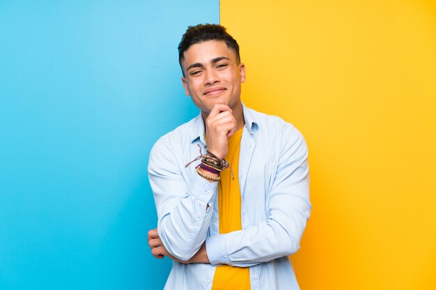 Young man over isolated colorful wall laughing