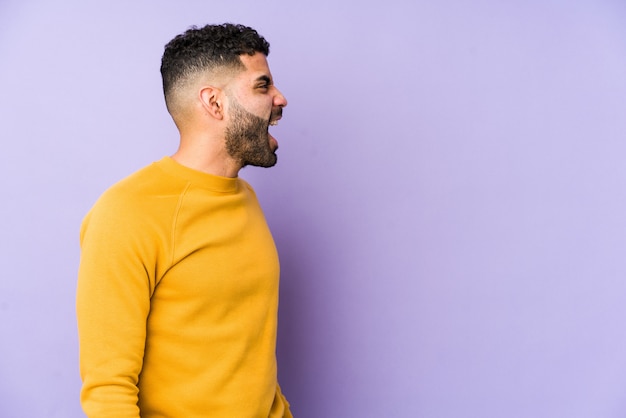 Young man isolated shouting towards a copy space