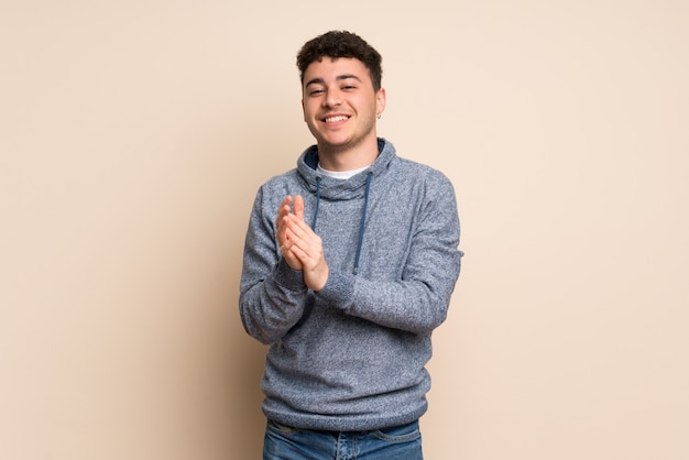 Young man over isolated wall applauding after presentation in a conference