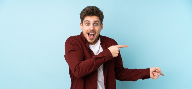 Photo young man isolated wall surprised and pointing side