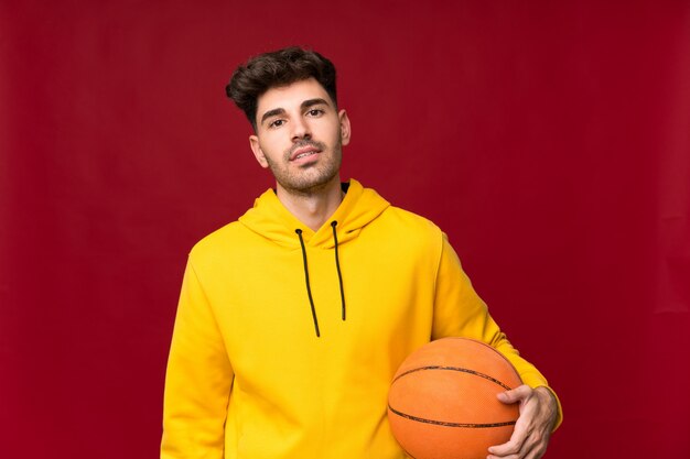 Young man over isolated wall with ball of basketball