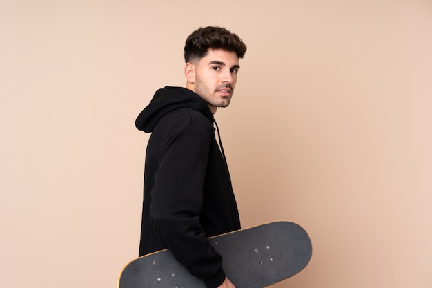 Young man over isolated wall with a skate