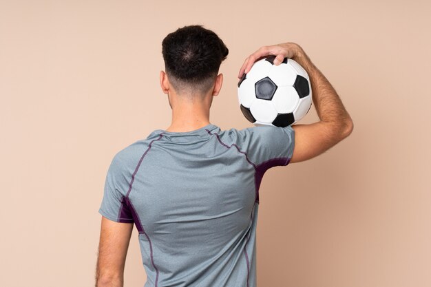 Молодой человек над изолированной стеной с футбольным мячом