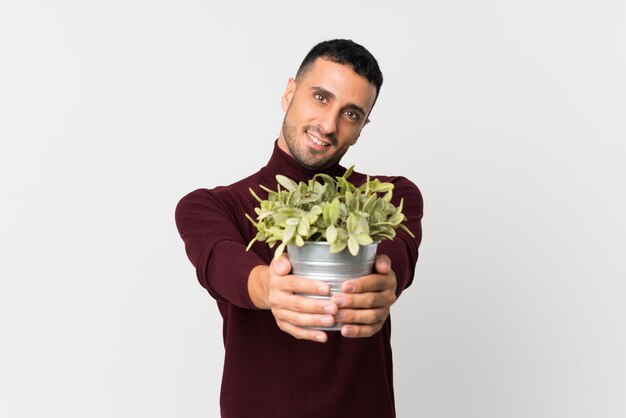 Young man over isolated white  taking a flowerpot