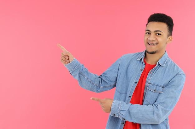 Young man in jeans shirt on pink background