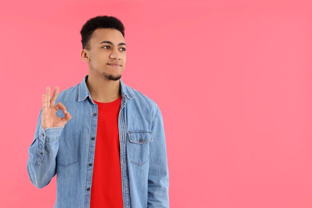 Young man in jeans shirt on pink background