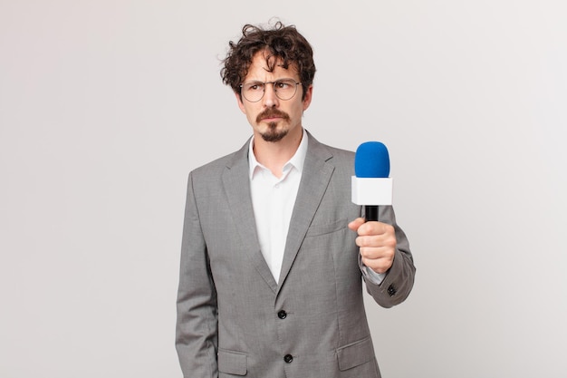 Young man journalist feeling sad, upset or angry and looking to the side