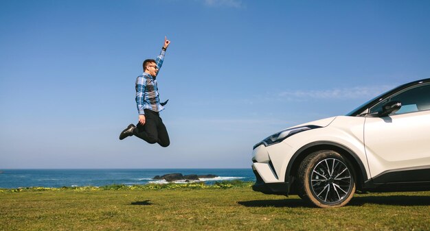 Photo young man jumping happy with car