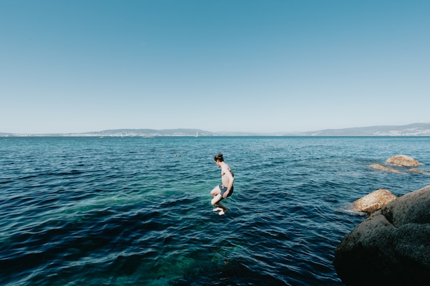 Young man jumping into the sea, in the air, mediterranean holidays, freedom and liberty concepts, modern, pale man