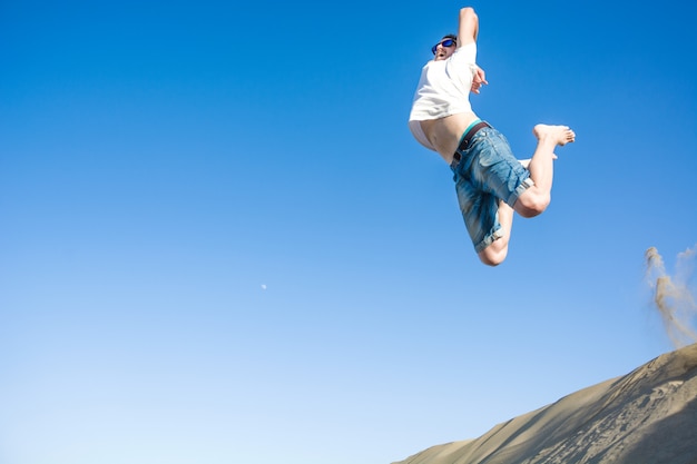 写真 若い男が砂丘にジャンプ