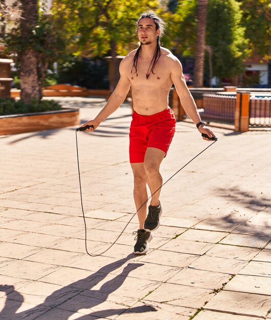 Young man jumping using rope at park