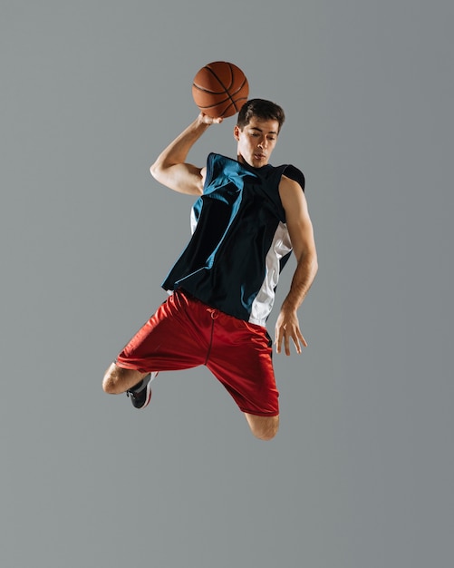 Young man jumping while playing basketball