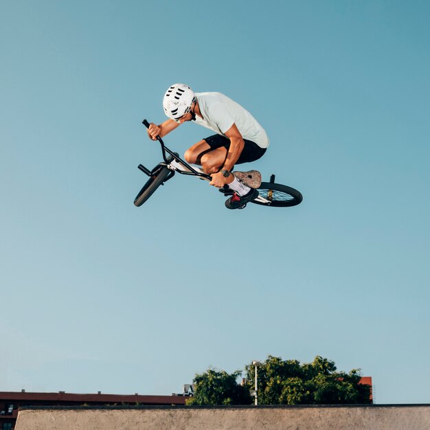 Il giovane che salta con la bici del bmx in uno skatepark