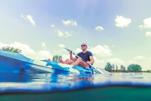 Foto giovane uomo kayak sul lago, kayak vista subacquea, colpo diviso.