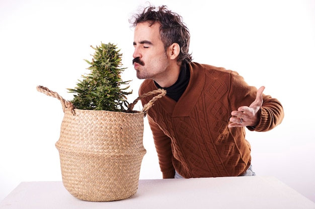 A young man kissing a marijuana plant on a white background