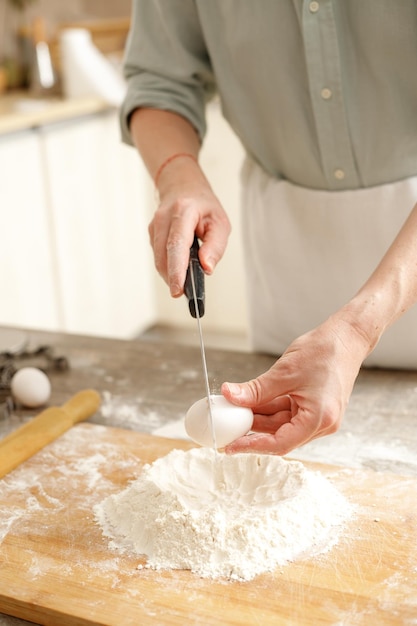 木製のテーブルの上でペーストを混ぜる若者 男性の手がキッチンでパンを作る ベーキングコンセプト