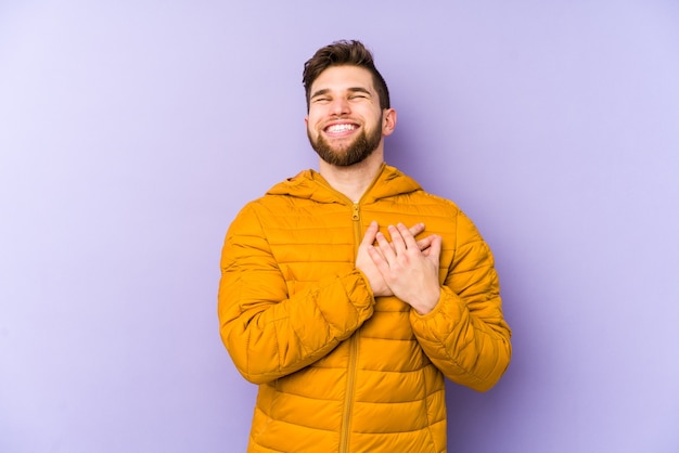 Young man laughing keeping hands on heart, concept of happiness.