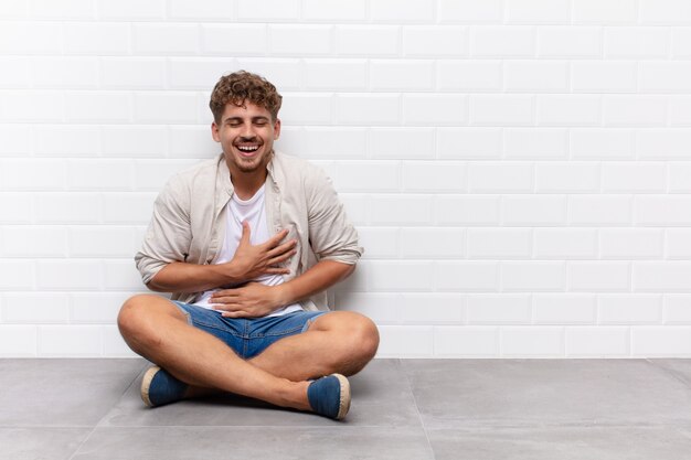 Young man laughing out loud at some hilarious joke, feeling happy and cheerful, having fun