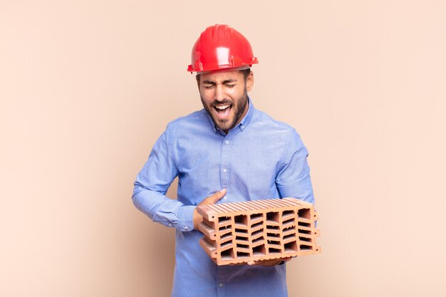 Young man laughing out loud at some hilarious joke, feeling happy and cheerful, having fun